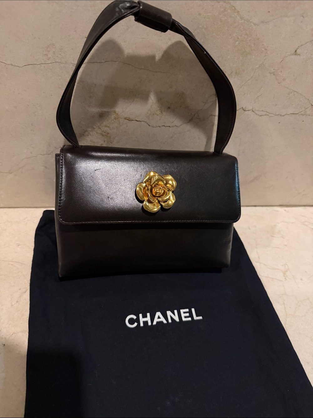 CHANEL Black Leather petite Bag with Gold Camellia Accent.